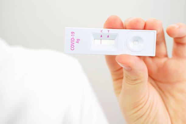 istock Female hand holding a plastic test for coronavirus close-up on white background. 1369920464