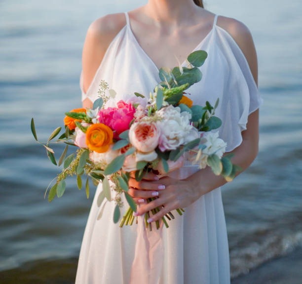 istock Bride holds wedding bouquet near sea 1369926364
