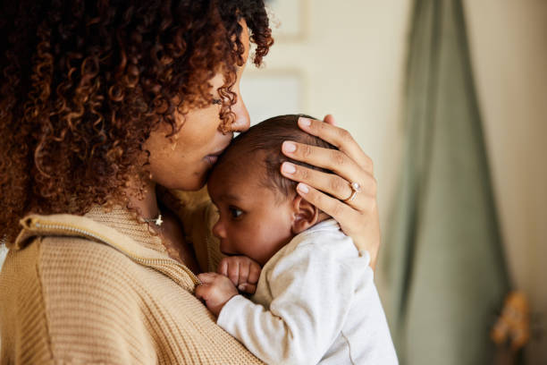 mère embrassant avec son petit garçon dans ses bras - afro photos et images de collection