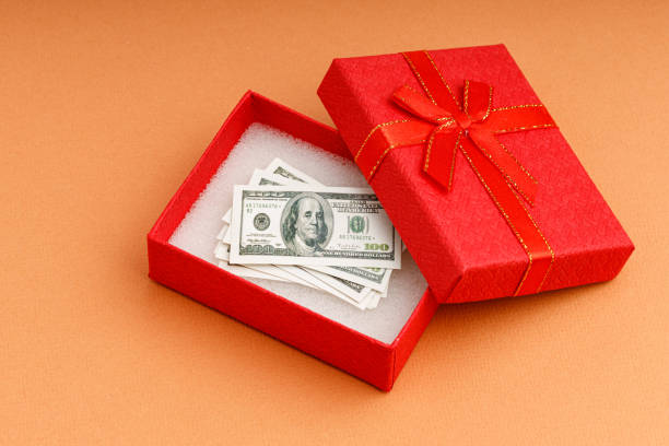 istock money as a gift, dollars in a red gift box 1369928107