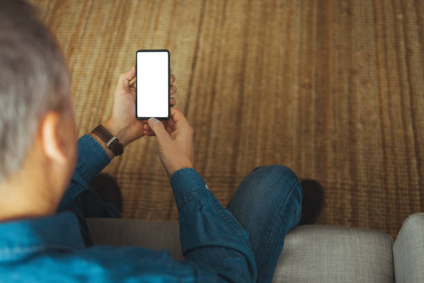 istock Man sitting on sofa watching multimedia content on a smartphone 1369934200