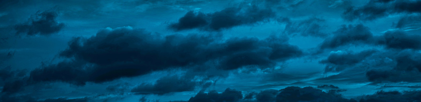 Clouds in the night sky. Black blue skies. Dark evening sky background with copy space for design. Wide banner.