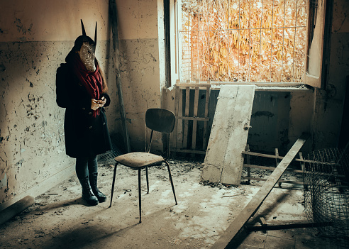 Young woman portrait wearing tribal mask in abandoned place