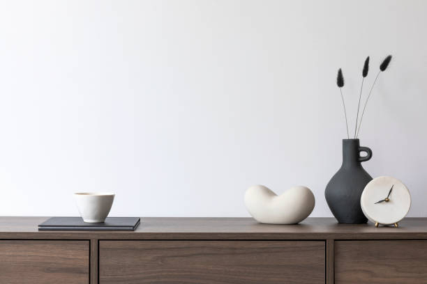 istock Stylish living room interior composition with brown wooden commode and small home decorations. White wall. Copy space. Template. 1369936189