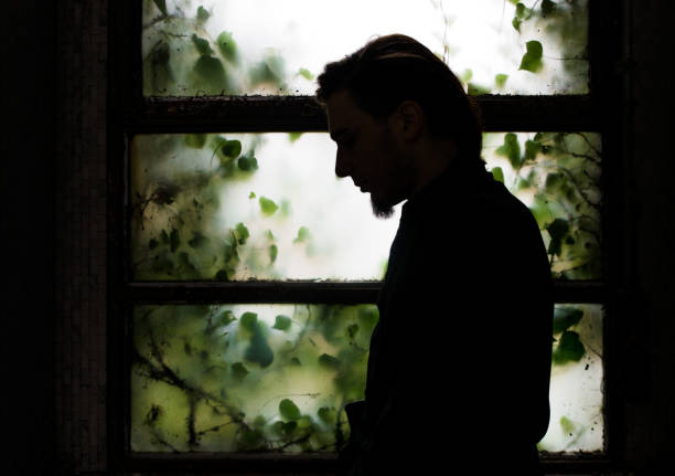 Young man silhouette in front of window in abandoned place