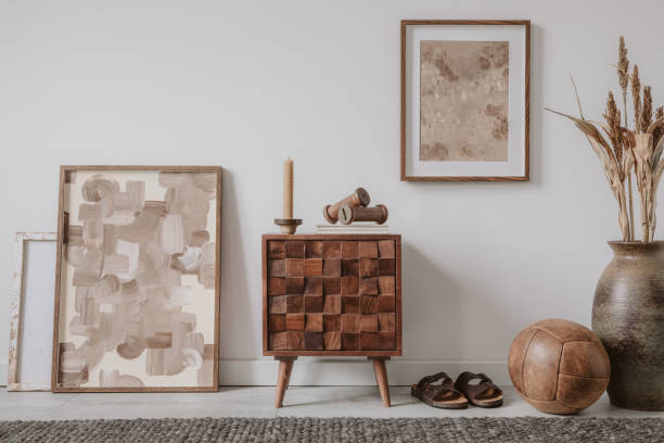 istock Stylish living room interior design with small wooden commode, mock up poster frame and creative accessories and home decor. Modern home staging. Template. Copy space. 