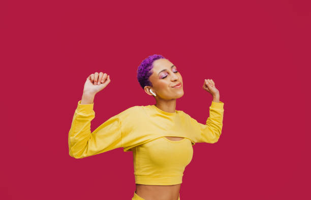 Enjoying the music Enjoying the music. Happy young woman dancing with her eyes closed while wearing wireless earphones in a studio. Woman with purple hair streaming her favourite music playlists. purple hair stock pictures, royalty-free photos & images