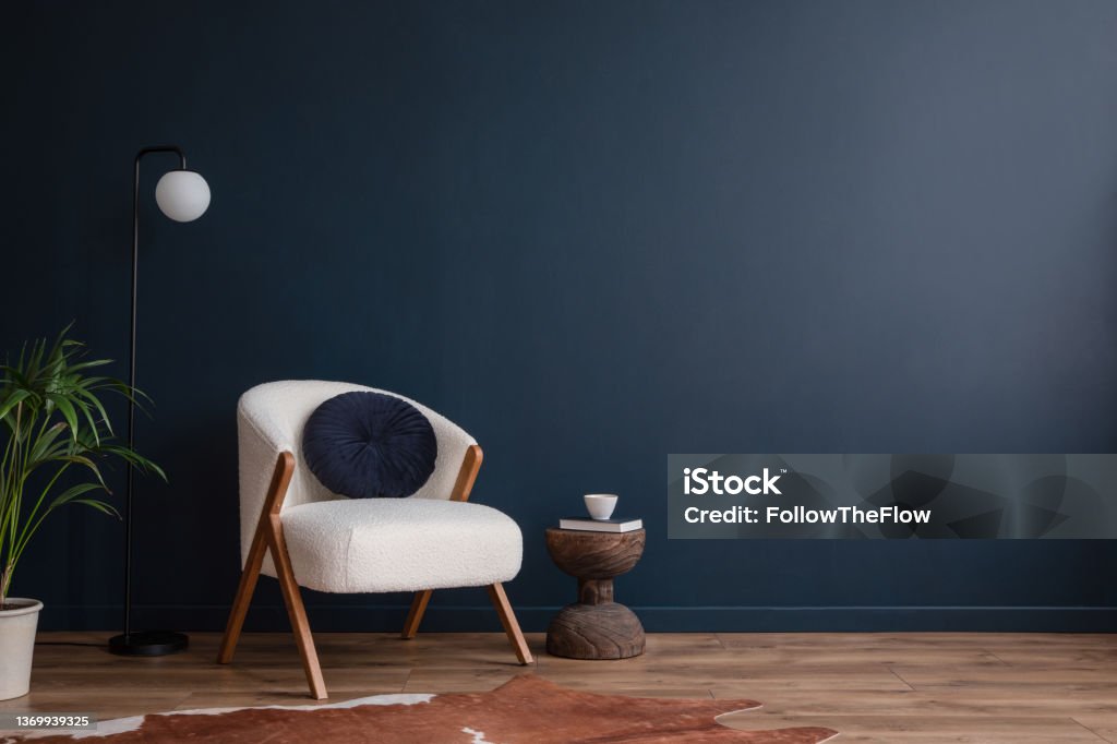 Stylish compositon of elegant living room interior design with fluffy armchair and modern home accessories. Blue wall. Home staging. Template. Copy space. Home Interior Stock Photo