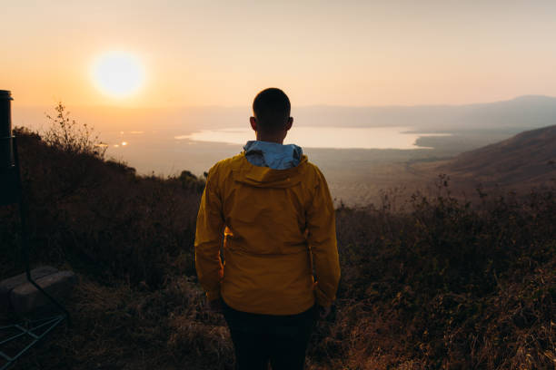 voyageur masculin contemplant le lever du soleil pittoresque au-dessus du cratère du volcan ngorongoro en tanzanie - african sunrise photos et images de collection