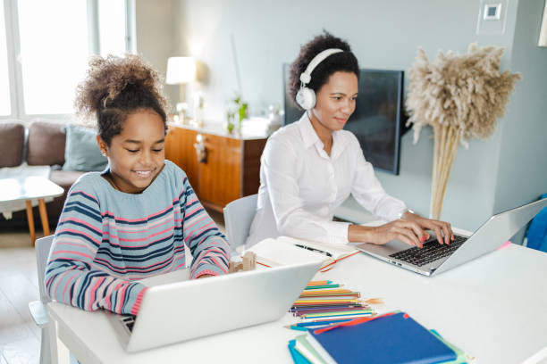 istock A mother works from home and her daughter sits at the table next to her studying 1369942004