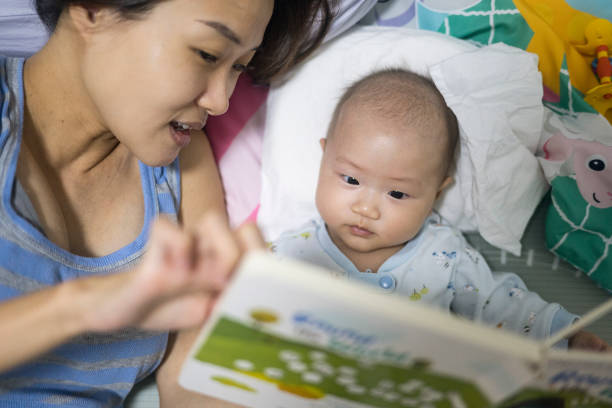 Asian mum reading bedtime story to baby stock photo