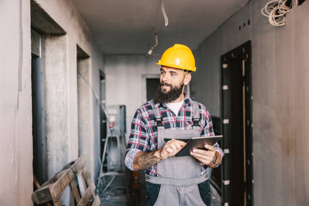 un lavoratore dedicato che utilizza il tablet per lavorare in un edificio in un processo di costruzione. - repairman foto e immagini stock