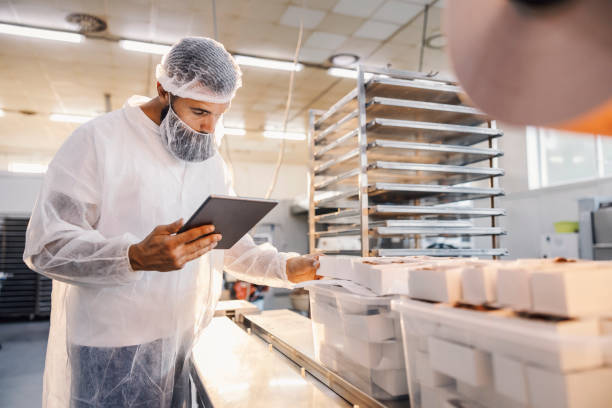 A food factory supervisor using tablet and assesses quality of food. stock photo