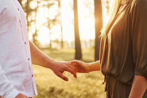 Focused view of hands. Happy couple is outdoors in the forest at daytime.