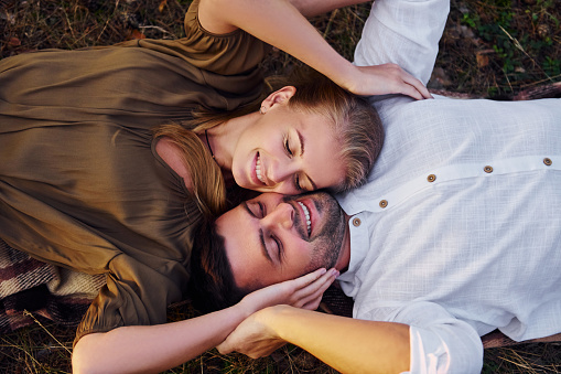 Happy couple is outdoors laying down on the ground.