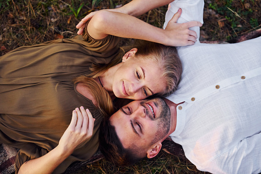 Happy couple is outdoors laying down on the ground.