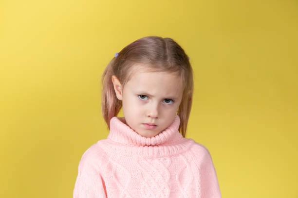 istock Sad caucasian elementary age school girl looking at the camera on yellow 1369947070