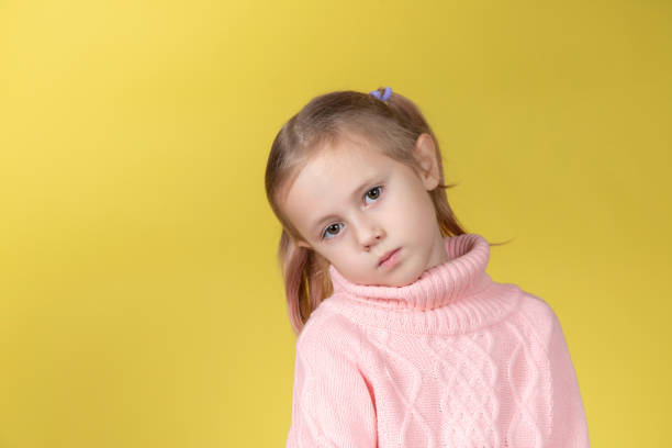 istock Sad caucasian elementary age school girl looking at the camera on yellow 1369947077