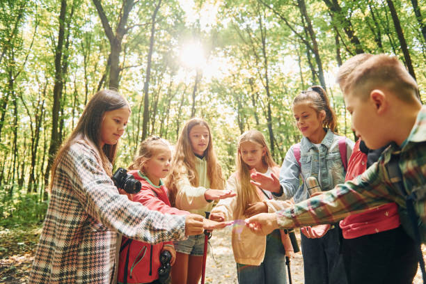 istock Using map. Kids in green forest at summer daytime together 1369948236