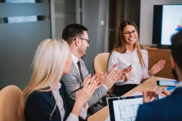 Cheerful businesspeople applauding a in a meeting at boardroom. Satisfied entrepreneurs clapping to a colleague in a meeting at boardroom. encouragement stock pictures, royalty-free photos & images