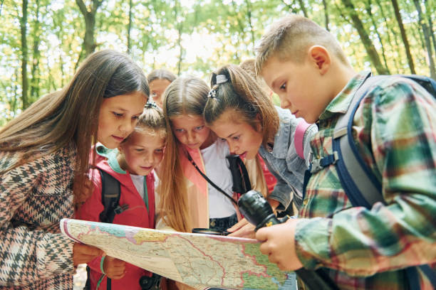 istock Using map. Kids in green forest at summer daytime together 1369948973