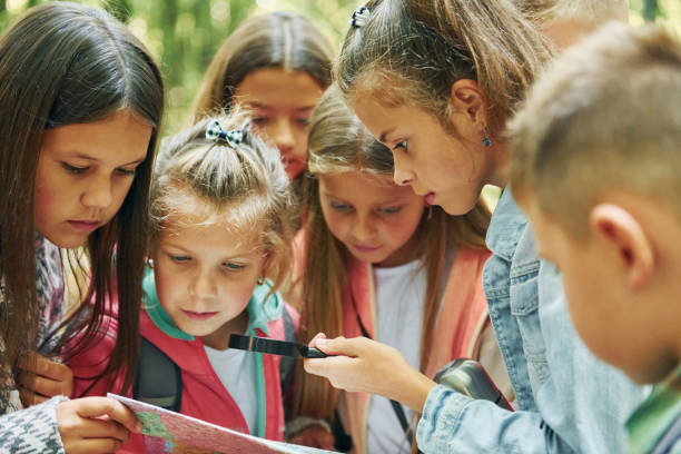 istock With map. Kids in green forest at summer daytime together 1369949063