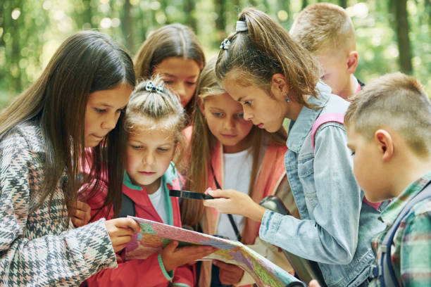 istock With map. Kids in green forest at summer daytime together 1369949307