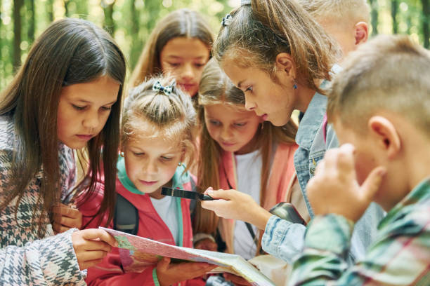 istock With map. Kids in green forest at summer daytime together 1369949309