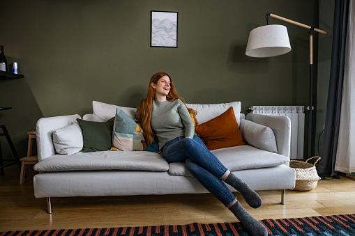 Photo of a woman sitting on the sofa at home