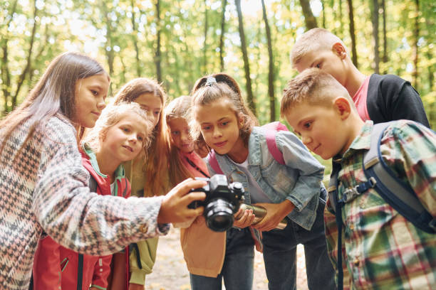 istock Front view. Kids in green forest at summer daytime together 1369950012