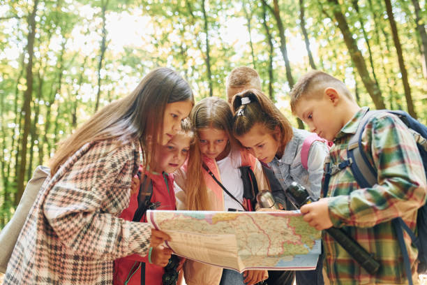 istock Front view. Kids in green forest at summer daytime together 1369950030