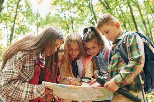 istock Front view. Kids in green forest at summer daytime together 1369950039