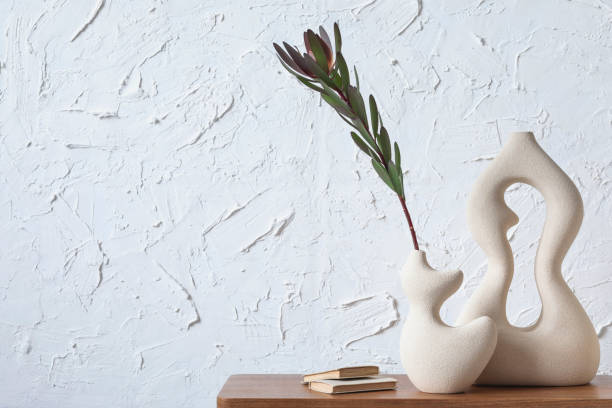 istock Creative minimalistic composition of home interior with handmade clay vases, sidetable and elegant personal accessories. Copy space. Wall paper. Template.