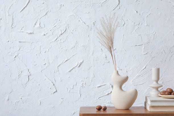istock Creative minimalistic composition of home interior with handmade clay vase, sidetable and elegant personal accessories. Copy space. Wall paper. Template.