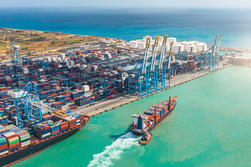 Aerial view of a huge port with containers and cargo ships entering the port for loading and unloading