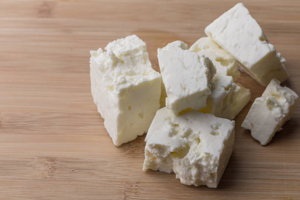 istock Soft white cheese cubes on wooden board with copy space 1369951710