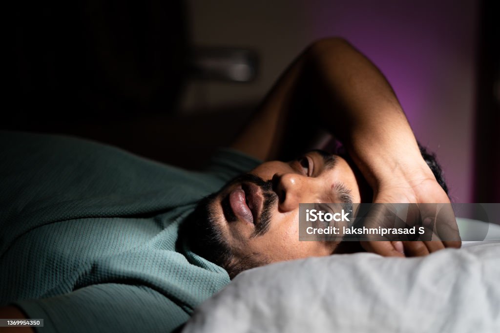 young man unable to sleep during night at bedroom - concept of suffering from insomnia, thoughtful and problems young man unable to sleep during night at bedroom - concept of suffering from insomnia, thoughtful and problems. Insomnia Stock Photo