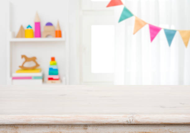 istock Empty table with blurred children toy shelf and window background 1369955757