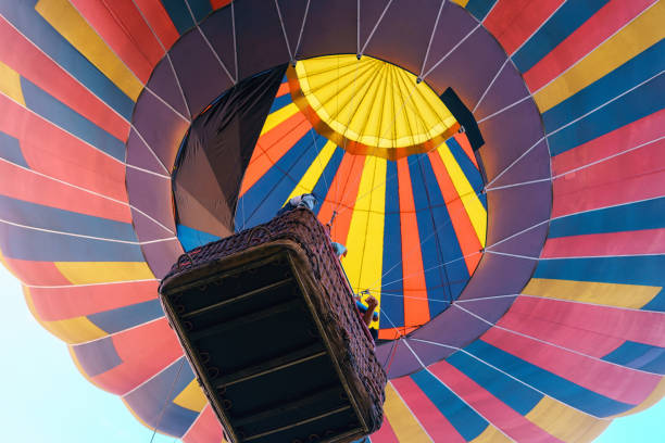 istock Multicolored hot air balloon with basket rises into the sky, bottom view 1369955783