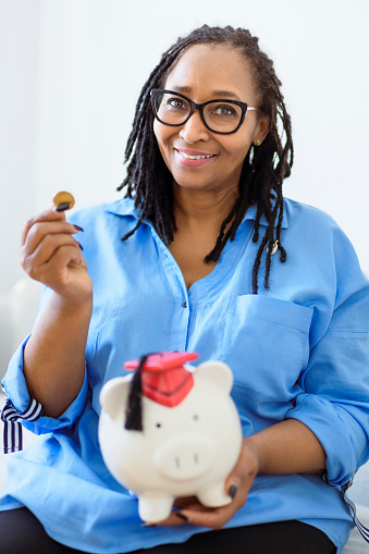 A Beautiful black woman holds a pink piggy bank representing savings and retirement