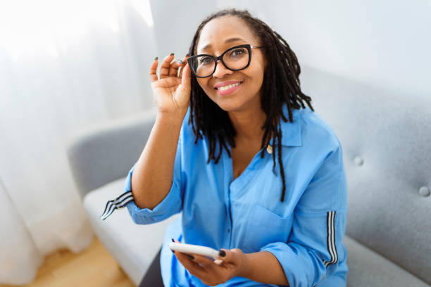 Portrait of an african woman sit on the sofa with cellphone stock photo