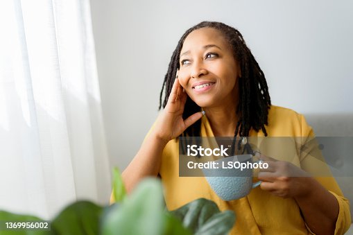 istock Portrait of an african woman sit on the sofa with coffee 1369956002