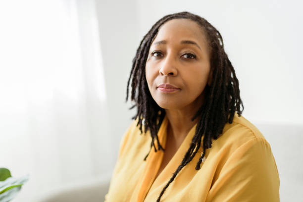 porträt einer afrikanischen frau, die auf dem sofa sitzt, sieht besorgt aus - women mature adult black american culture stock-fotos und bilder
