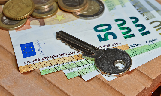 A key on euro coins and banknotes on a brick.