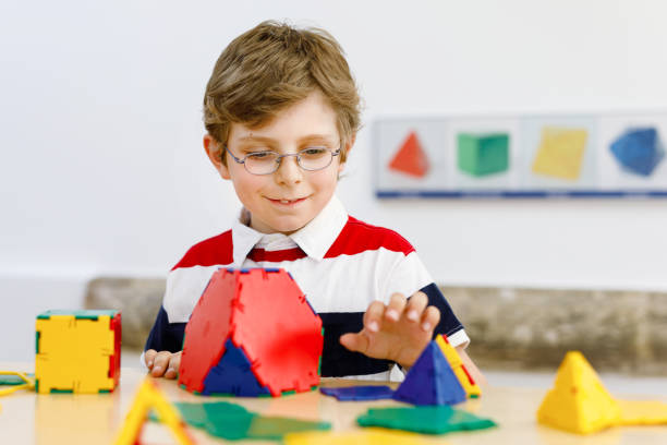 istock Happy kid boy with glasses having fun with building and creating geometric figures, learning mathematics and geometry 1369960884