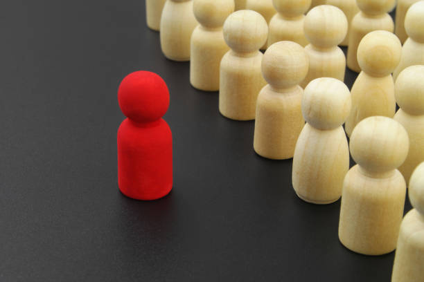 istock Wooden figure stand in rows and red leader. 1369962162
