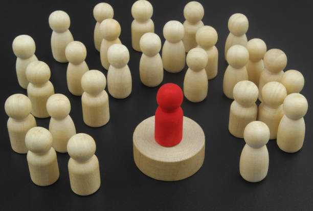 red wooden figure as leader surrounded by many figures. - surrounding leadership organization meeting imagens e fotografias de stock