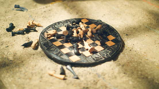 Chess gameplay on desert. Postapocalyptic mood, abandoned camp