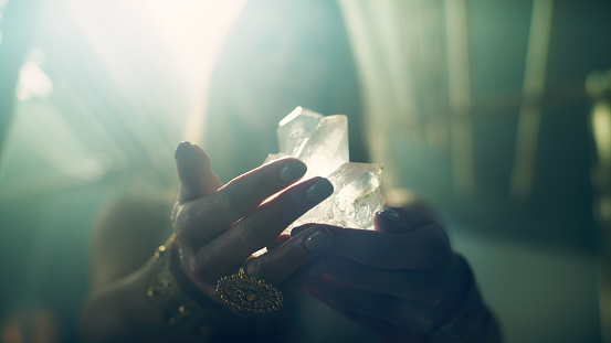 Magic ritual in desert tent. Woman's hand with a healing crystal.