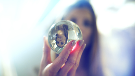 Cropped hand holding crystal ball against sea